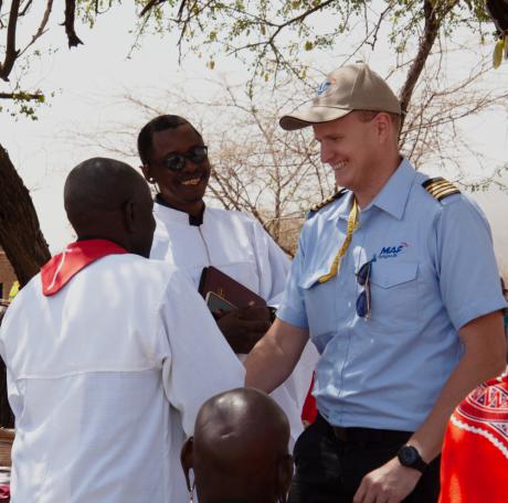 MAF Pilot Peter Griffin shaking hands with the son of a previous traditional healer, as MDTC founder evangelist Elisha Moita joins in the joy of seeing lives changed by the love of Christ