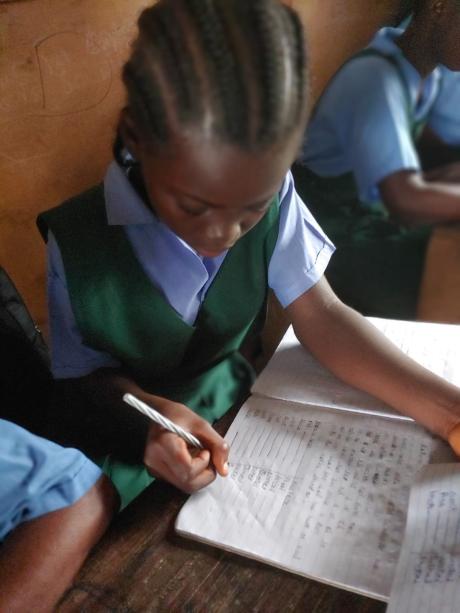 Dougbe River Presbyterian student in a class writing a not